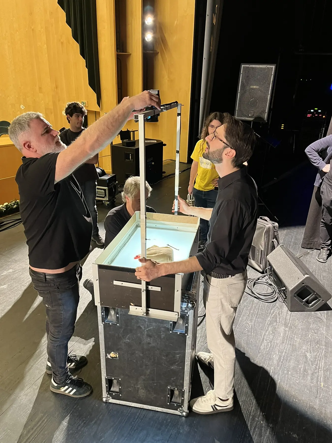 TK preparing the sand-art table backstage with a production team