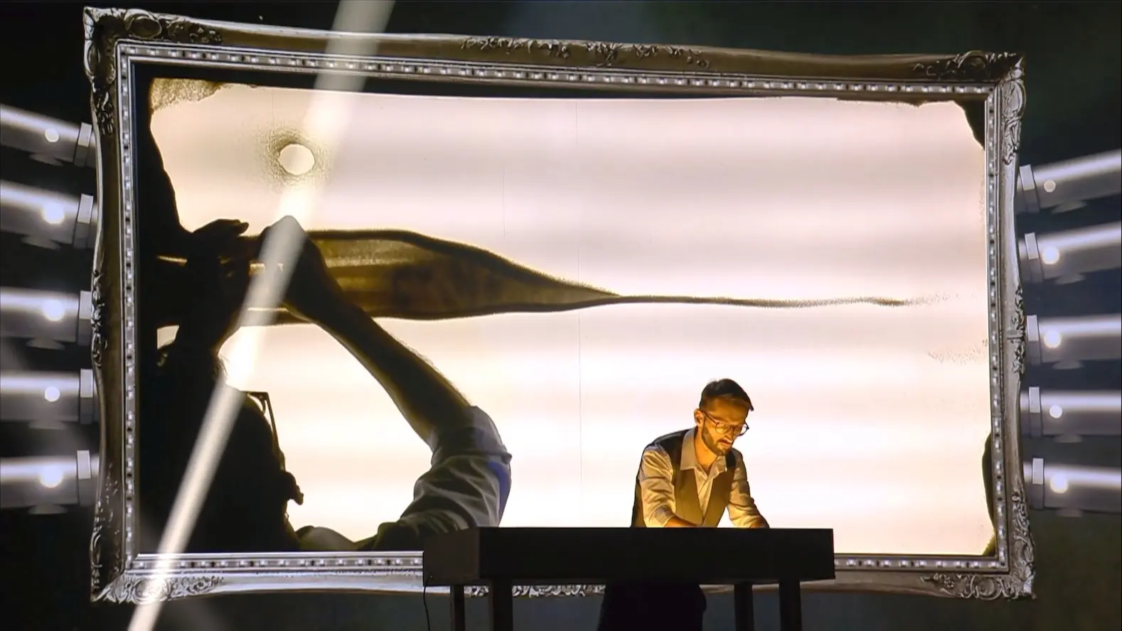 TK creating a live sand-art performance on stage